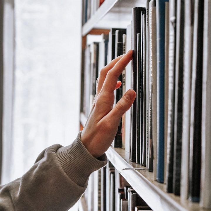 The Bid Library A bid writer's hand reaching for documents on the shelf of a bid library.