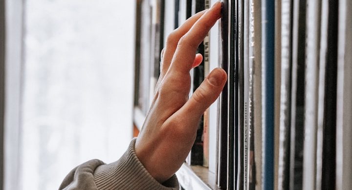 Bid writer reaching for documents stored on a bid library shelf.